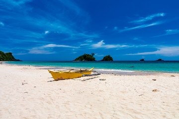 Small wooden boats on a beautiful tropical beach surrounded by crystal clear ocean