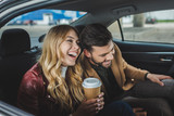 Fototapeta  - happy young couple laughing while sitting together in taxi