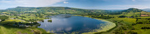 Aerial Panoramic View Of A Beautiful Natural Lake Surrounded By Rural Farmland (Llangorse Lake, Wales)
