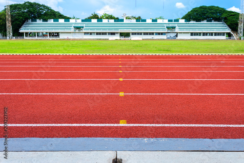 Fotomural White lines of stadium and texture of running racetrack red rubber racetracks in outdoor stadium are 8 track and green grass field,empty athletics stadium with track,football field, soccer field
