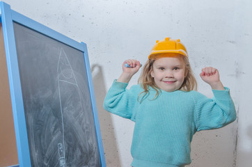 girl in a helmet paint a house on a chalk Board