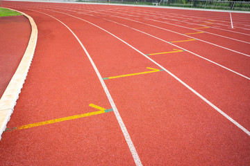 White lines of stadium and texture of running racetrack red rubber racetracks in outdoor stadium are 8 track and green grass field,empty athletics stadium with track.