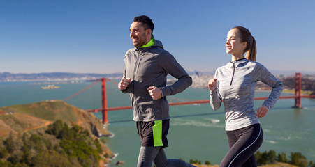 Sticker - fitness, sport, people and healthy lifestyle concept - happy couple running over golden gate bridge in san francisco bay background