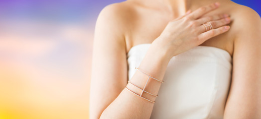 beauty, jewelry and luxury concept - close up of beautiful woman with golden ring and bracelet over pastel background