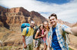 © Syda Productions - travel, tourism and technology concept - group of smiling friends or travelers with backpacks taking selfie over rocks of grand canyon national park background