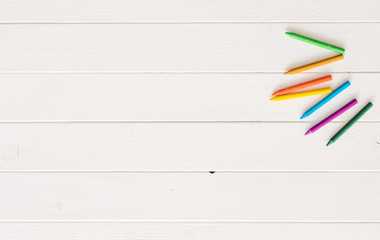 colorful wax crayons for drawing on the white wooden table. top view and copyspace. space for captio