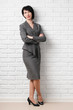 © soleg - business woman dressed in a gray suit poses in front of a white wall