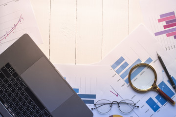 Magnifying glass and documents with analytics data lying on table,selective focus