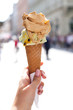melting delicious ice cream in waffle cone gelato pistachio salty caramel holding female hand