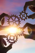 © gerasimov174 - Four hands of businessmen collect the gear from the gears of the details of the puzzles. against the background of sunlight. Concept business idea. Teamwork, cooperation, strategy
