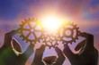 © gerasimov174 - three hands of businessmen collect the gear from the gears of the details of the puzzles. against the background of sunlight. Concept business idea. Teamwork, cooperation, strategy
