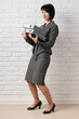 © soleg - business woman with folder, dressed in a gray suit poses in front of a white wall