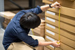 Young Asian man using tape measure for measuring dimension of product in cardboard box. Shopping lifestyle in warehouse concept