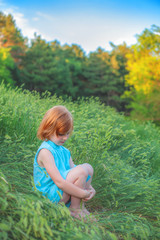 Wall Mural - The girl is sitting on the edge of the forest