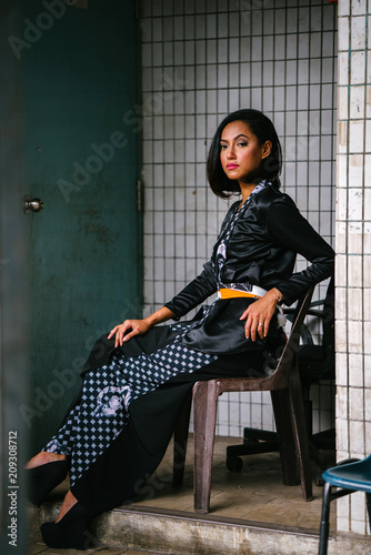 Fotografía Fashion portrait of a young, slim, attractive and fashionable Muslim Malay woman sitting and posing on a chair in a city in Asia