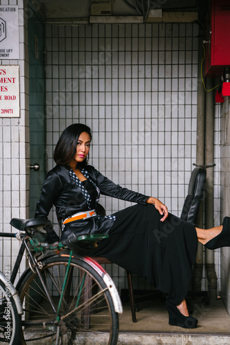 Fotografía Fashion portrait of a young, slim, attractive and fashionable Muslim Malay woman sitting and posing on a chair in a city in Asia