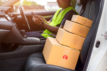 The dispatcher uses the delivery program using a mobile phone. In the van with parcels on the outside of the warehouse.