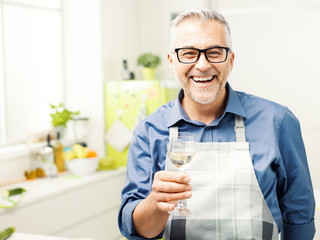 Man having a glass of wine in the kitchen