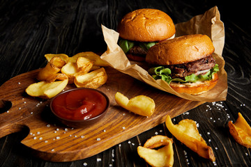 tempting fast food diner with burgers and potatoes with sauce on cutting board