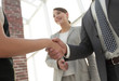© ASDF - Businesspeople  shaking hands against room with large window loo