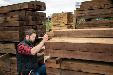 Wall Mural - Lumber yard worker, carpenter at wood yard counts inventory with mobile device