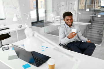 Canvas Print - business, people and technology concept - african american businessman with smartphone at office