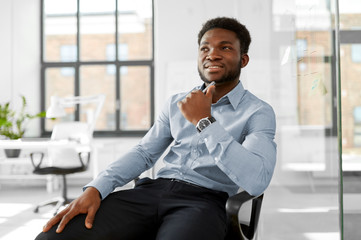 Wall Mural - business and people concept - smiling african american businessman sitting on office chair