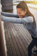 © Flamingo Images - Smiling young Asian woman stretching outdoors before exercising