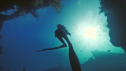 Wall Mural - freediver ascending to water surface from wreck in deep ocean