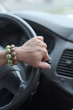 © Anna Jurkovska - Men's hand with bracelets amulets on the steering wheel of the car