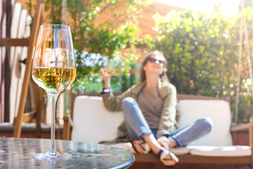 Wall Mural - glass of chilled white wine on table over young woman and Tuscany backgound