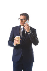 serious businessman in eyeglasses talking on smartphone and holding paper cup of coffee isolated on white background