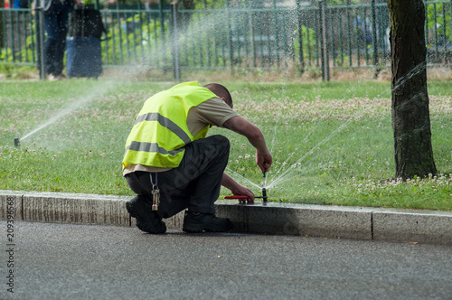 Fotografía transportation company employee adjusting automatic sprinklers on tramway line