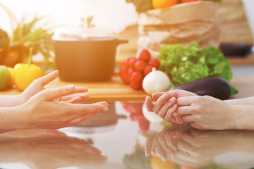 Closeup of human hands cooking in kitchen. Women discuss a menu. Healthy meal, vegetarian food and lifestyle concept