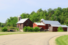 Agriculture And Farming Background. Rural Life Concept.Scenic Countryside Spring Landscape With Rural Road Along Farm Buildings And Ted Barns On A Woods Background. Midwest USA,Wisconsin,Madison Area.