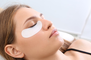 Poster - Young woman undergoing eyelash extensions procedure, closeup