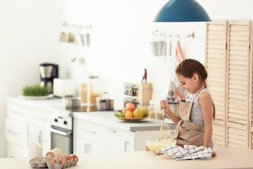 Poster - Little girl making dough at table in kitchen