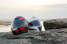 Two Helmets Stand On A Stone, Near The Lake At Sunset