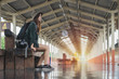 Traveler woman sitting and waits train on railway platform