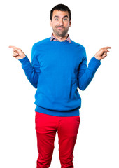 Handsome young man pointing to the laterals having doubts on white background