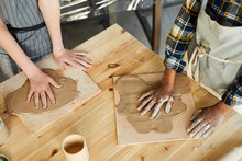 Two Schoolkids Making Handprints On Rolled Pieces Of Clay On Wooden Boards At Handcraft Lesson