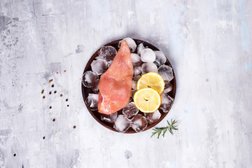 Wall Mural - Fresh raw meat chicken breast on a wooden plate with lemon slice and ice. Lean proteins.