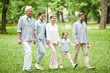 © pressmaster - Senior and young couples and little girl walking down green glade in park on summer day