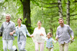 © pressmaster - Happy couples and little girl running in summer park or forest on hot day