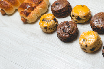 closeup delicious sausage bread roll and fresh tasty scones on wooden table