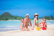 © travnikovstudio - Family of four making sand castle at tropical white beach
