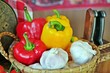 Fresh, raw vegetables for cooking:colorful bell peppers and garlics in a basket with knifes background. Selective focus. Close up.