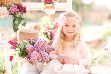 Smiling kid girl 4-5 year old posing with flowers outdoors. Summer time.