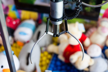 Claw crane capture device in the amusement park for the kids. Toy catcher game in the kids park. Claw crane game concept with blurred background. Kids amusement park.