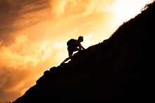 Man Hiker Climbing Up A Steep Mountain Cliff.  People Taking Risk, Motivation And Outdoor Adventure Concept. 